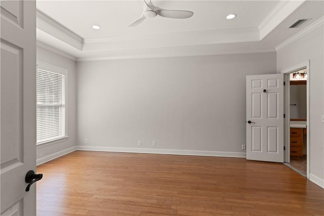 spare room featuring ceiling fan, light hardwood / wood-style floors, a raised ceiling, and ornamental molding