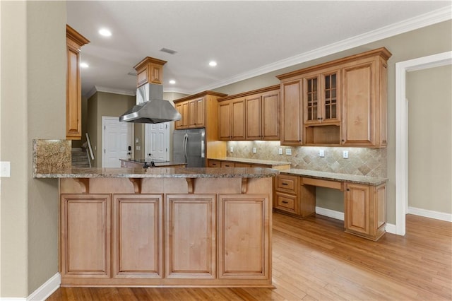 kitchen with light hardwood / wood-style flooring, kitchen peninsula, stainless steel fridge, crown molding, and island range hood