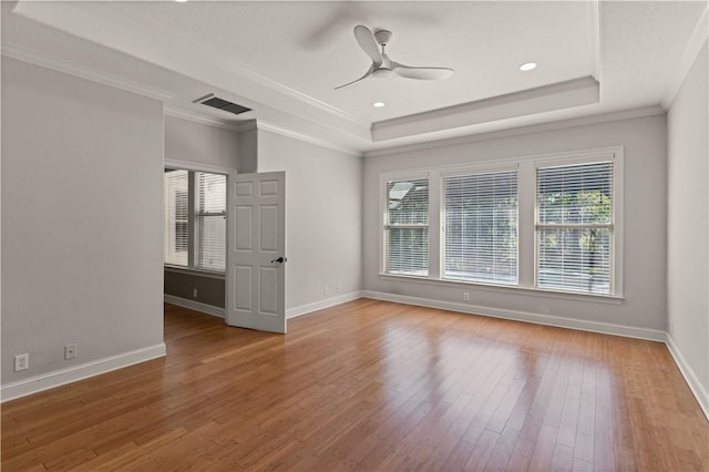 unfurnished room with wood-type flooring, a raised ceiling, ceiling fan, and crown molding