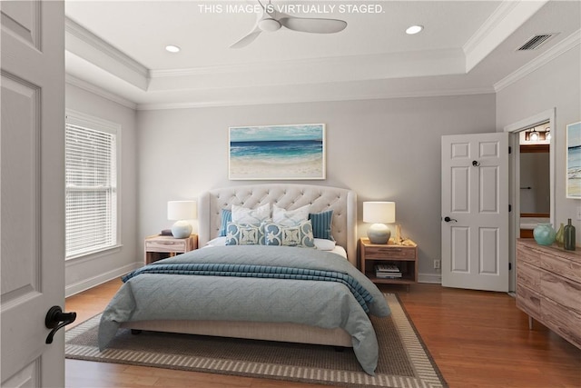 bedroom with wood-type flooring, a raised ceiling, ceiling fan, and crown molding