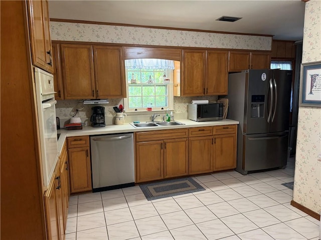 411 Whitefield Ave, Saint Simons Island, GA 31522 - kitchen featuring stainless steel appliances, wallpapered walls, a sink, and brown cabinets