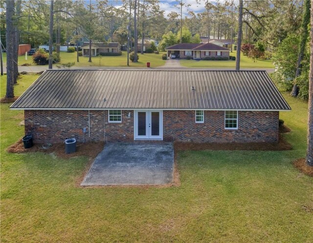 rear view of property with a yard, brick siding, metal roof, and a patio area