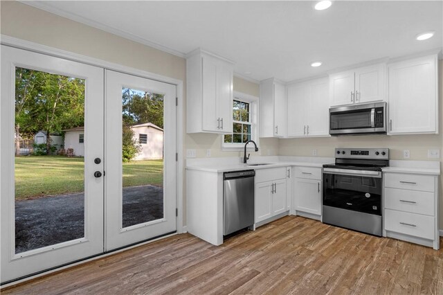 kitchen with stainless steel appliances, light wood-style flooring, light countertops, and white cabinets