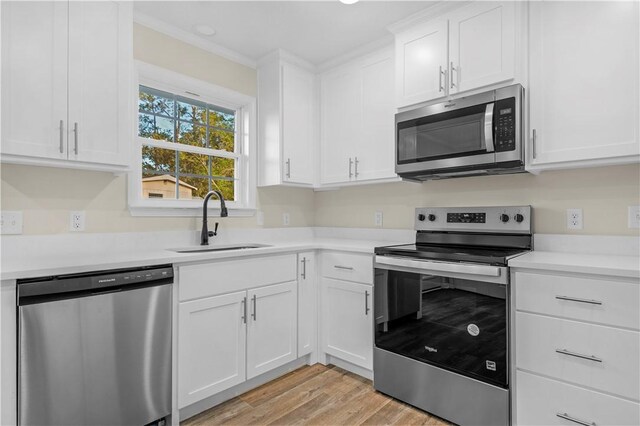kitchen with light wood-style floors, appliances with stainless steel finishes, a sink, and white cabinets