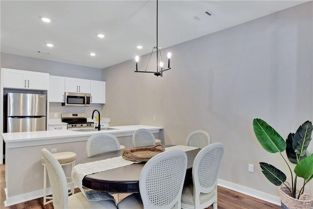 dining area featuring dark hardwood / wood-style flooring, sink, and a chandelier