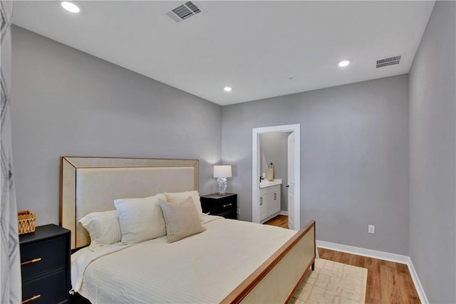 bedroom with light hardwood / wood-style floors and connected bathroom