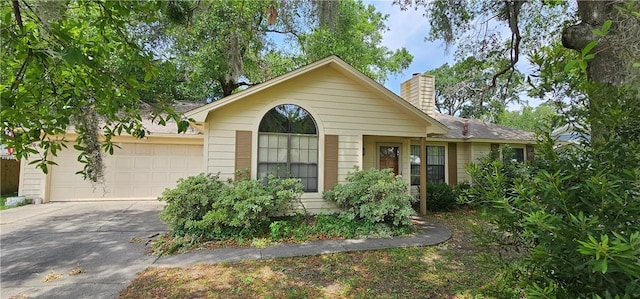 single story home featuring driveway, a chimney, and a garage