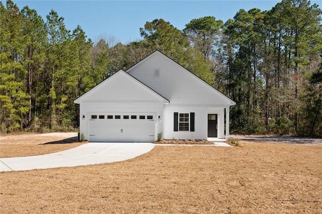 view of front of home with a garage, concrete driveway, and a view of trees