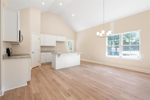 kitchen featuring high vaulted ceiling, white cabinetry, a kitchen breakfast bar, light wood-style floors, and range