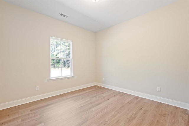 unfurnished room with light wood-type flooring, visible vents, and baseboards