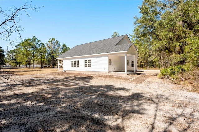 view of side of property with a shingled roof and a patio area