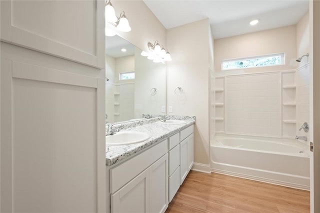 full bath featuring double vanity, wood finished floors, shower / bath combination, and a sink