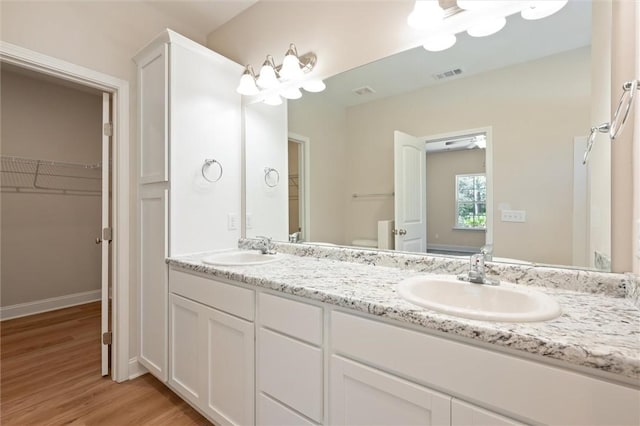 full bath featuring double vanity, visible vents, a sink, and wood finished floors