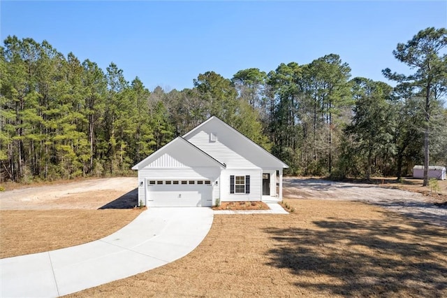 view of front facade with a garage, a forest view, and concrete driveway