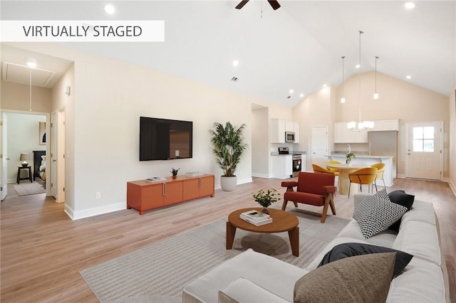 living room with light wood-style floors, attic access, high vaulted ceiling, and a ceiling fan