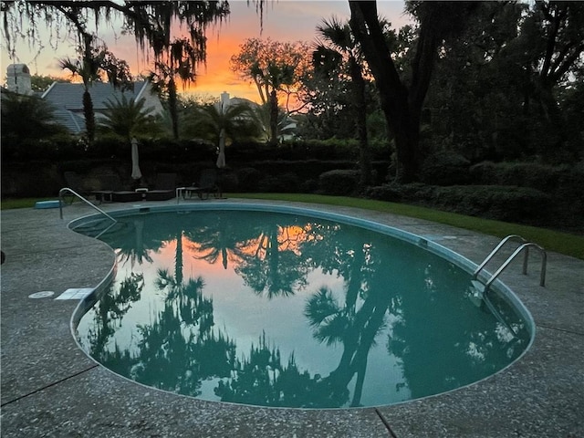 pool at dusk featuring a patio area