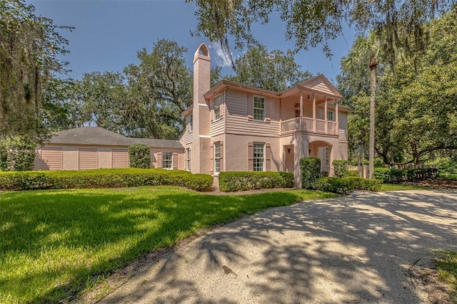 view of front of property with a balcony and a front lawn