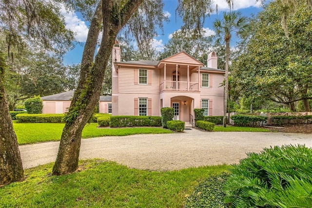 view of front facade featuring a balcony and a front lawn