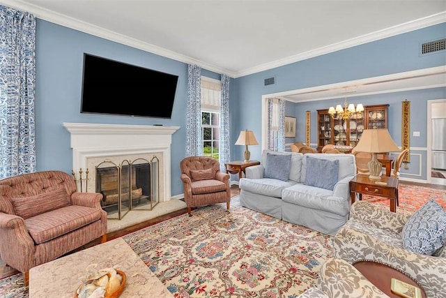 living room featuring a notable chandelier, ornamental molding, and a premium fireplace