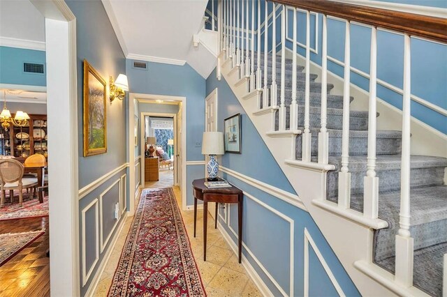 stairway with crown molding and a notable chandelier