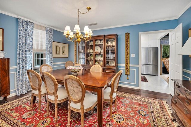 dining area with an inviting chandelier, dark hardwood / wood-style floors, and ornamental molding