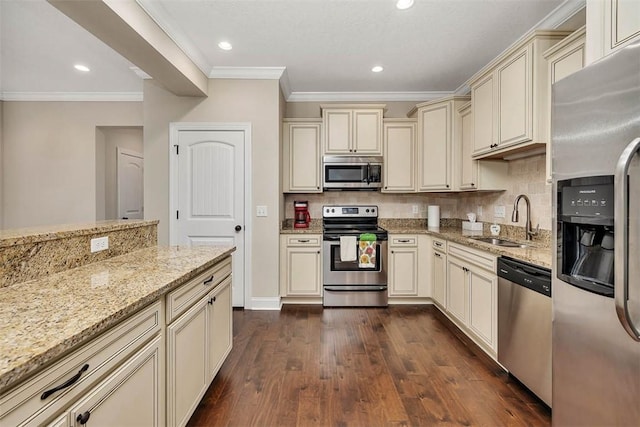 kitchen with cream cabinets, stainless steel appliances, sink, and light stone countertops