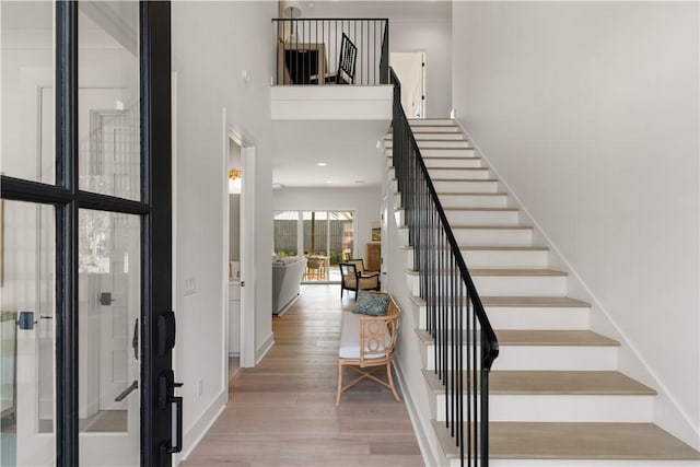 foyer entrance featuring stairway, baseboards, a high ceiling, and wood finished floors