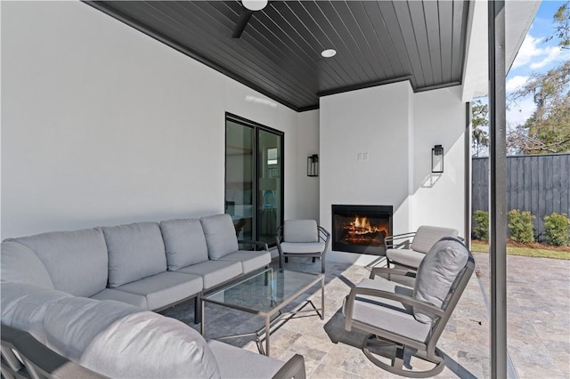 view of patio / terrace featuring fence, a ceiling fan, and an outdoor living space with a fireplace