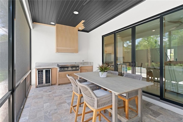 616 Neptune Way, Saint Simons Island, GA 31522 - sunroom featuring beverage cooler, an outdoor kitchen, a sink, a ceiling fan, and outdoor dining area
