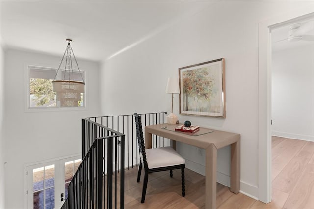 hall featuring baseboards, an upstairs landing, a wealth of natural light, and wood finished floors