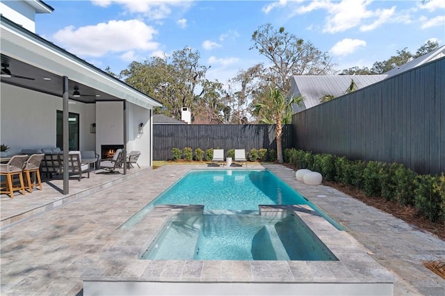 view of swimming pool featuring a pool with connected hot tub, ceiling fan, outdoor lounge area, a fenced backyard, and a patio