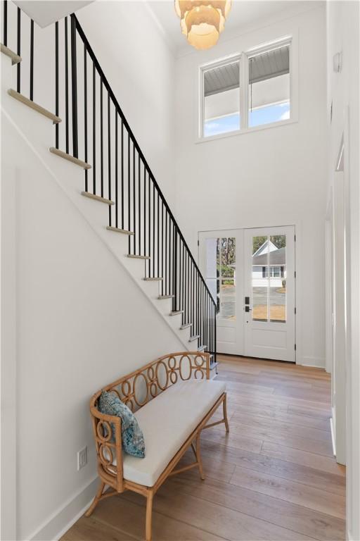 entryway featuring wood finished floors, baseboards, a high ceiling, and stairway