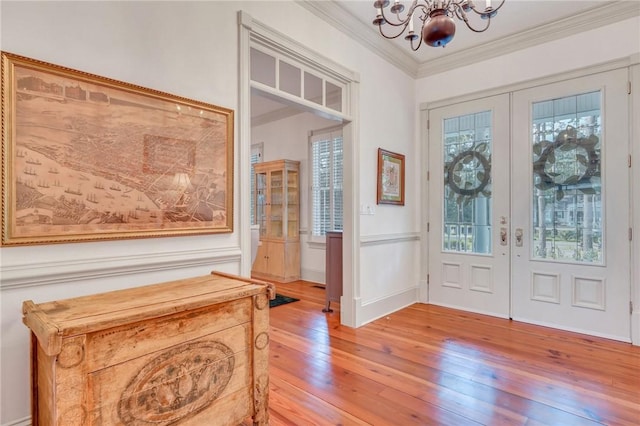 foyer entrance with hardwood / wood-style flooring, a chandelier, ornamental molding, and french doors