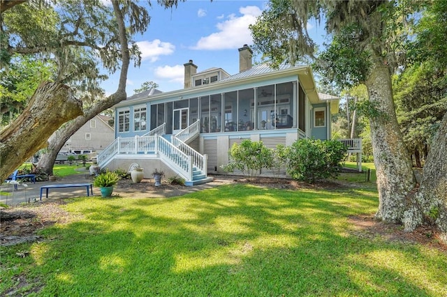 rear view of property featuring a sunroom and a yard