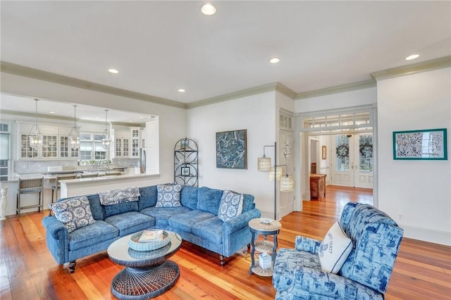 living room with light wood-type flooring, crown molding, and french doors