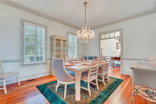 dining area with a chandelier, plenty of natural light, ornamental molding, and hardwood / wood-style flooring