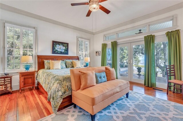 bedroom with multiple windows, ceiling fan, french doors, and hardwood / wood-style flooring