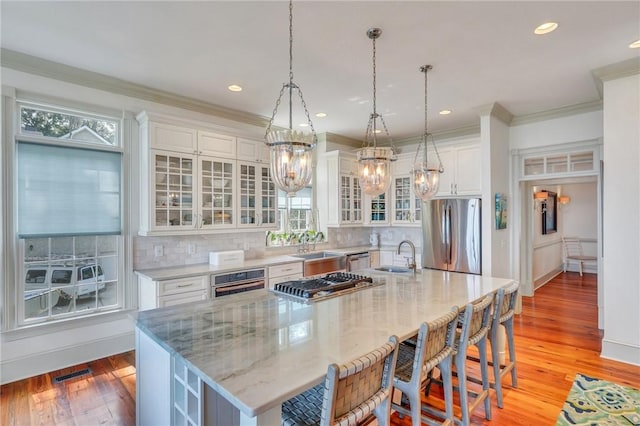 kitchen with white cabinetry, a center island with sink, pendant lighting, and appliances with stainless steel finishes