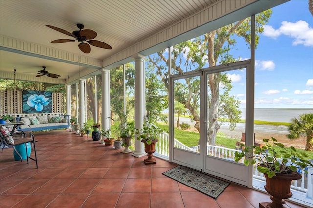 sunroom with a water view and ceiling fan