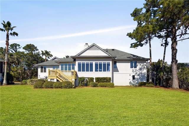 back of house featuring a sunroom, a deck, and a lawn