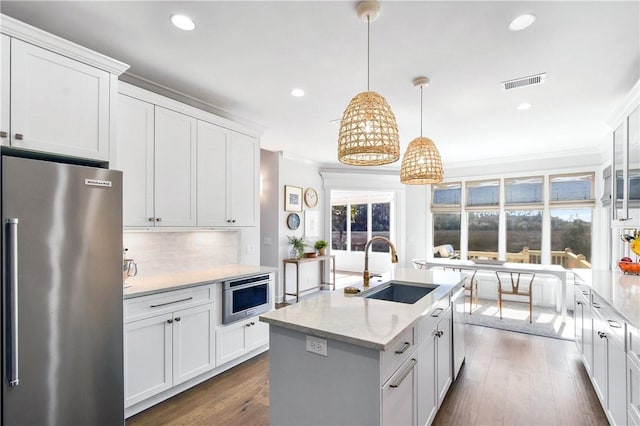 kitchen with sink, appliances with stainless steel finishes, light stone countertops, white cabinets, and decorative light fixtures