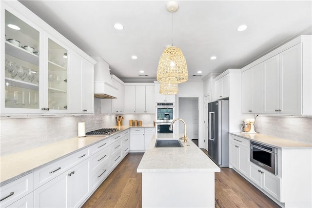 kitchen with sink, white cabinetry, stainless steel appliances, an island with sink, and decorative light fixtures