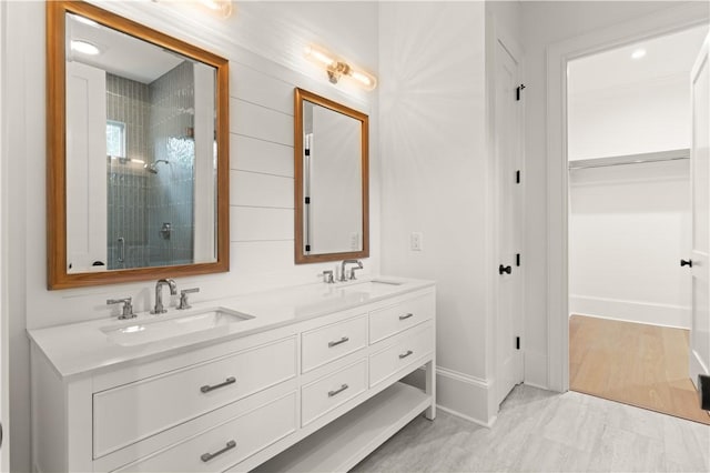 full bath featuring a shower stall, double vanity, and baseboards