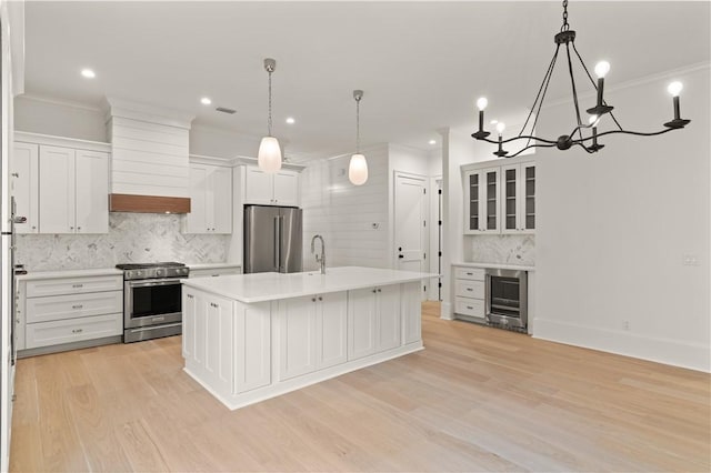 kitchen with high end appliances, light countertops, tasteful backsplash, light wood-style floors, and a sink