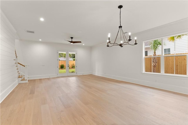 empty room featuring stairs, baseboards, light wood-style flooring, a chandelier, and a ceiling fan
