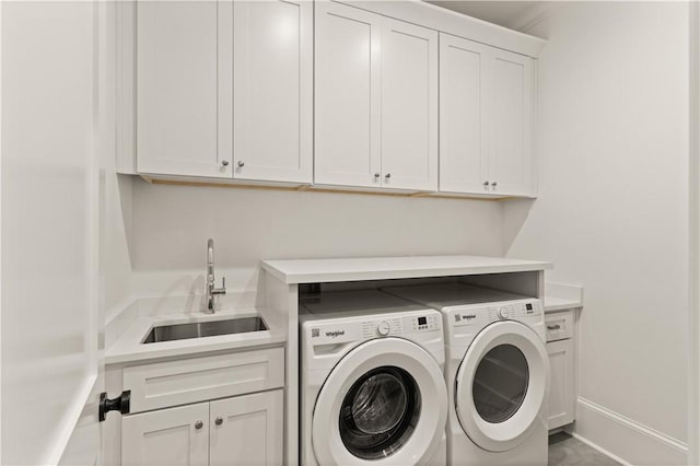 clothes washing area featuring washing machine and clothes dryer, cabinet space, and baseboards