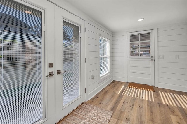 doorway to outside featuring wood walls and light hardwood / wood-style flooring