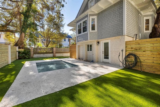 back of property featuring a patio area, a yard, and a fenced in pool