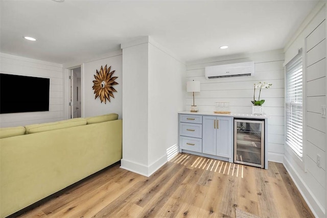 bar featuring an AC wall unit, beverage cooler, and light hardwood / wood-style flooring