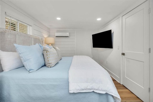 bedroom featuring ornamental molding, a wall mounted air conditioner, and hardwood / wood-style flooring